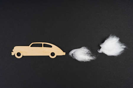 Environmental concept. Wooden car with traces of CO-2 emissions - cotton wool. Isolated on a black background.の写真素材