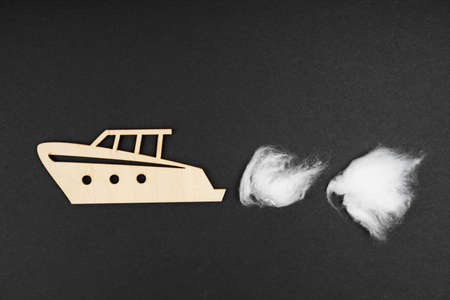 Environmental concept. Wooden boat with traces of waste discharge - cotton wool on a black background. Isolated.の写真素材