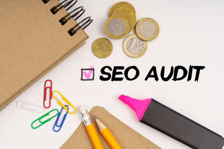 Business and finance concept. On a white background notepads, paper clips, coins, pencils and the inscription - SEO AUDITの写真素材