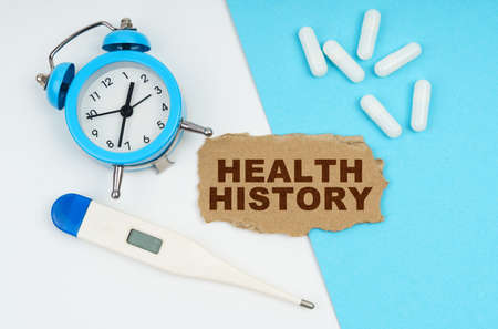 Medical concept. A clock, a thermometer, a syringe and a cardboard with the inscription - HEALTH HISTORYの写真素材
