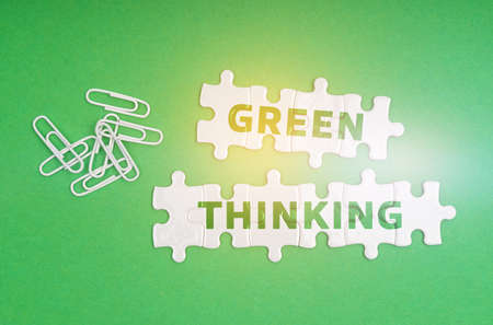 Ecology concept. On a green background, paper clips and white puzzles with the inscription - Green Thinkingの写真素材