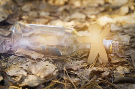 Ecology and medicine concept. A wooden figure of a man points to a glass alcohol bottle.の写真素材