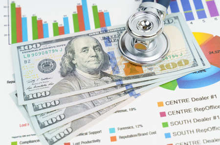Finance and economics concept. Coins and a stethoscope are on the documents with graphs and diagrams.の写真素材
