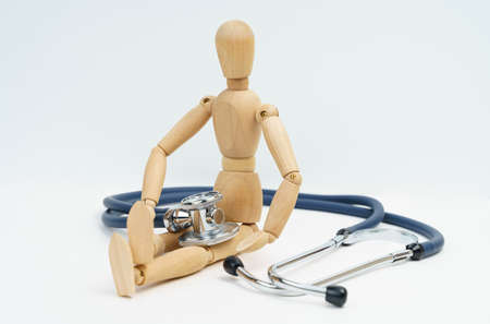 Medicine and health concept. A wooden man sits on a white background, next to him and on him is a...