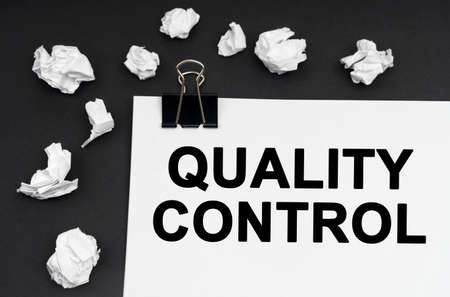 Industrial concept. On a black background, there are crumpled pieces of paper and paper with the inscription - Quality Controlの写真素材