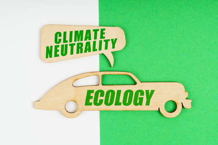 Environmental concept. On a white and green background, a wooden figure of a car with the inscription Ecology and a plate with the inscription - climate neutralityの写真素材