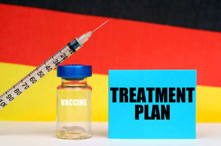 Medicine concept. Vaccine, syringe and blue plate with the inscription - TREATMENT PLAN. In the background the flag of Germanyの写真素材