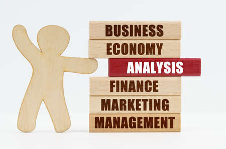Business and economy concept. On a white background, a wooden man stands and pushes out of the wall a red wooden plate with the inscription - ANALYSISの写真素材