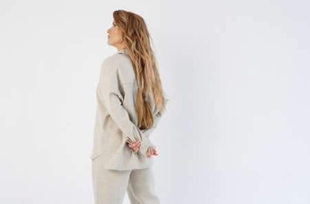 The woman holds her hands behind her back, crossing them. Isolated on white background.の写真素材