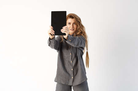 Business lady. Portrait of a business woman, stands holding a tablet in front of her, looks at the camera.の写真素材