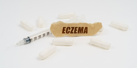 On a white table are pills, a syringe and a piece of paper with the inscription - ECZEMAの写真素材