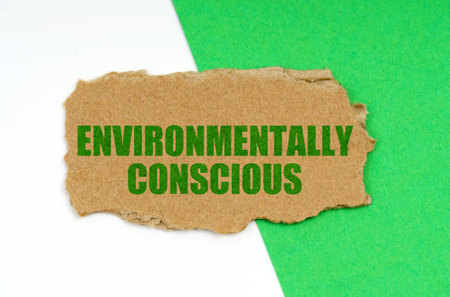 Environmental concept. On a white-green background lies a piece of cardboard with the inscription - Environmentally Consciousの写真素材