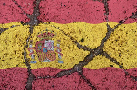 Spain flag on cracked asphalt. The concept of crisis, default, economic collapse, pandemic, conflict, terrorism in the country. Out of focus imageの写真素材