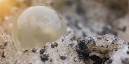 The glass ball lies on a dirty snowdrift nearby. Ecology concept.の写真素材