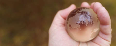 Environment concept. World earth day. Hands are holding a glass planet.