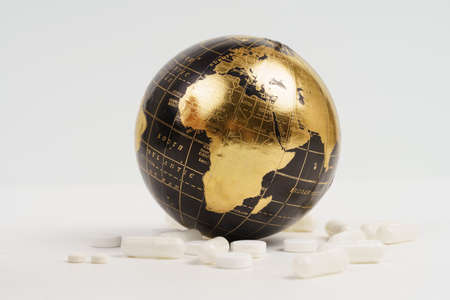 Global diseases and treatment. There are medicines near the black and golden globe - covered by a pandemic. Isolated on white background.の写真素材