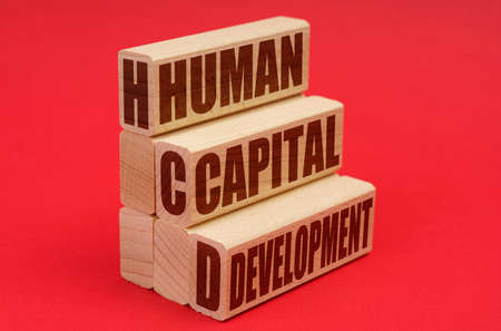 On a red background, wooden blocks with the inscription - Human Capital Developmentの写真素材