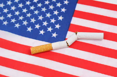 No smoking concept. A broken cigarette is on the US flag as a symbol of the harm of smoking.の写真素材