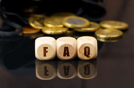 On a black surface are coins and cubes with the inscription - FAQの写真素材