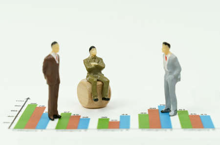 business concept. On the financial charts there are miniature figures of businessmen, one is sitting...