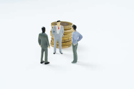 business concept. On the white surface of the coin, figures of businessmen stand nearby - they are...