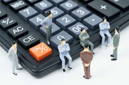 business and finance concept. On the calculator and next to it there are miniature figures of businessmen - they are conferring.の写真素材