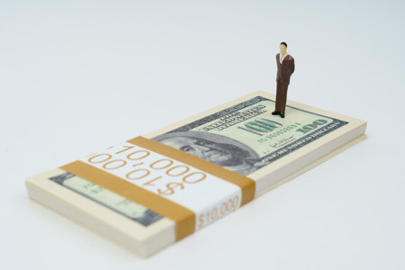 business concept. On a white surface lies a pack of dollars, on which stands a miniature figurine of a businessman.の写真素材