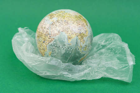 On a green surface, the planet stands on a plastic bag.の写真素材