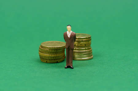 Miniatures. On the green surface are coins and a miniature figurine of people.の写真素材