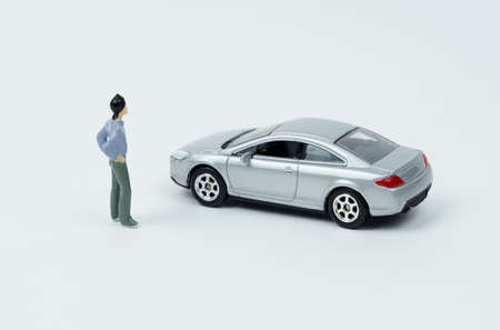 industry and technology concept. On a white surface is a car and a miniature figurine of a man looking at the car.の写真素材