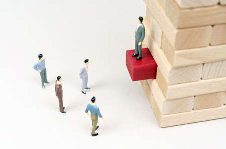leader concept. On a white surface, a leader stands on wooden blocks, figures of people are below.