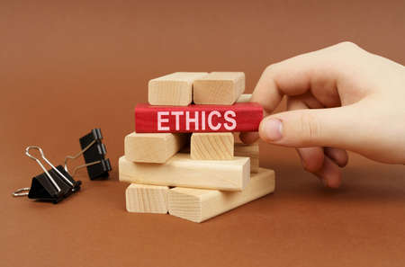 business concept. Clamps and wooden blocks lie on a brown surface, a person takes out a red block...