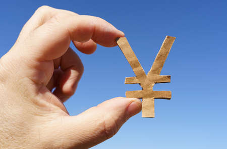 currency symbols. Against the background of the sky in the hands of a man the symbol of the yenの写真素材