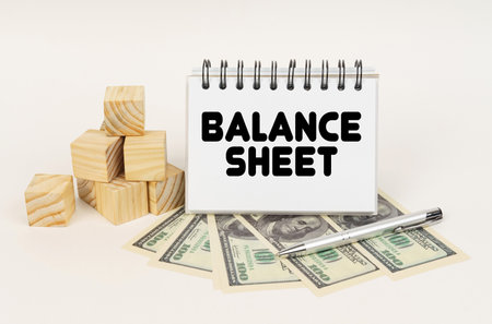 business concept. On a white surface, cubes, dollars, a pen and a notepad with the inscription - Balance Sheetの写真素材