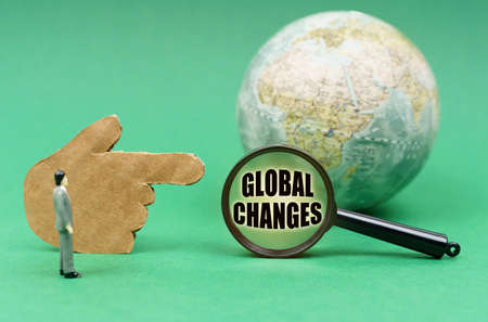 business concept. On a green surface is a globe, a hand and a magnifying glass with the inscription...