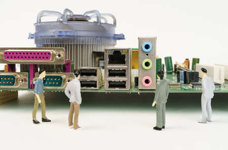 computer technology concept. Near the motherboard of the computer are miniature figurines of people....