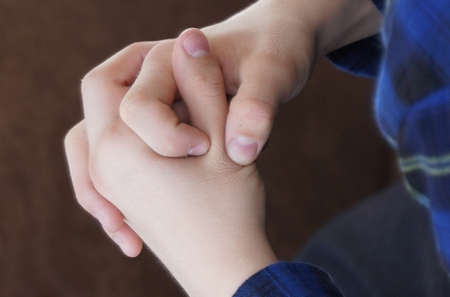 emotions. The teenager sits and clasps his hands. Close-up of hands.