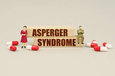 medical concept. Next to the miniature figurines of people are tablets and wooden blocks with the...