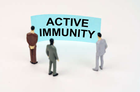 medical concept. Miniature figures of people stand in front of a blue sign with the inscription - Active Immunityの写真素材