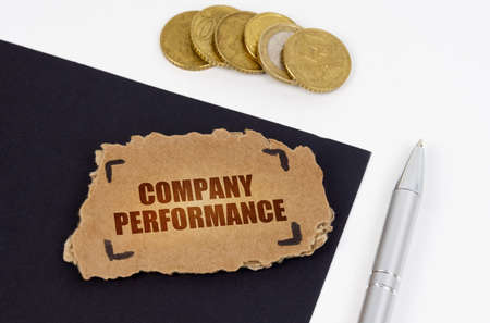 business concept. On a black and white surface lies a pen, coins and a cardboard sign with the...