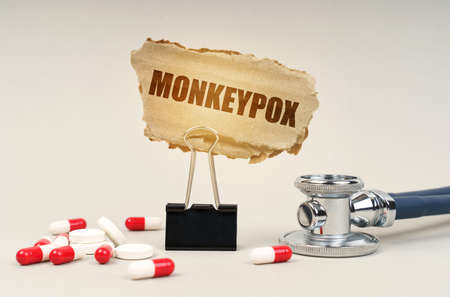 medical concept. Near the stethoscope are pills and a clip with a cardboard sign - monkeypox