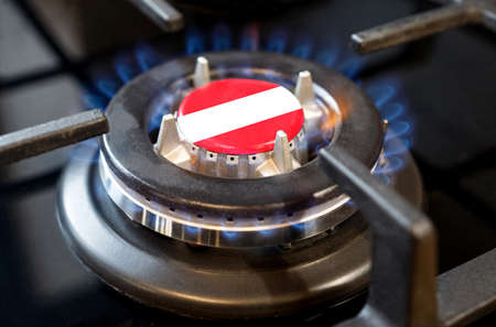 Gas import and export concept. A burning gas burner of a home stove, in the middle of which a flag...