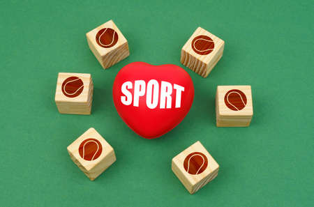 sports concept. On a green surface, a heart with the inscription - sports and cubes with a baseball ballの写真素材