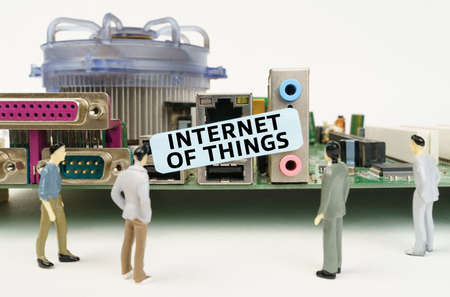 technology and computer concept. Figures of people are standing near the motherboard and looking at the sticker with the inscription - Internet Of Thingsの写真素材