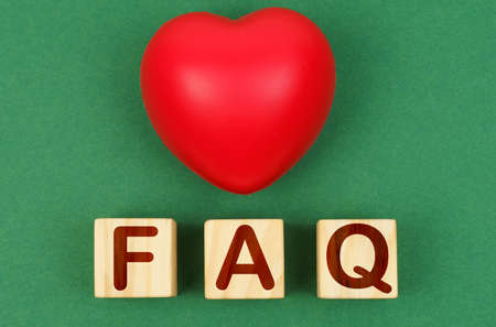 On a green surface is a red heart and cubes with the inscription - FAQ