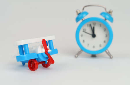 Airplane toy with alarm clock on blue. Time to flight.