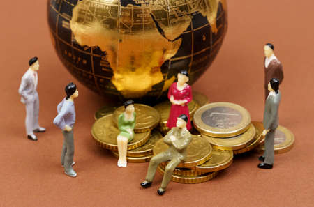 Global and business concept. Miniature business people stand near a globe and coins.