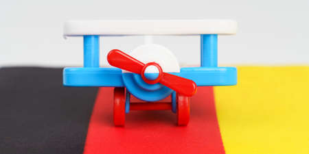 A toy plane stands on the flag of Germany. travel and business concept