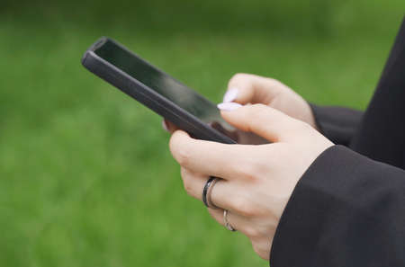 A woman is typing a message on her smartphone. Close-up of hands.の写真素材