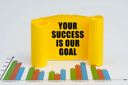 business concept. Against the background of the graphs, a yellow paper plate with the inscription - Your Success is Our Goalの写真素材